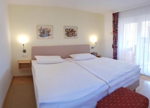 a bedroom with two white beds and a red chair at Ferienwohnung Graf Düne in Ostseebad Karlshagen