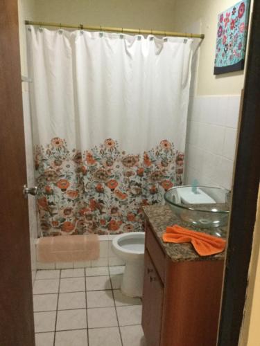 a bathroom with a shower curtain and a toilet at Sueños del Mar in Fajardo