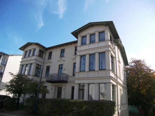 a large white building with windows on a street at Villa Goodewind 100 m zum Strand in Ahlbeck