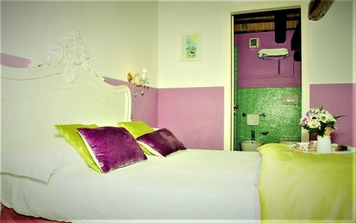 a bedroom with a white bed with purple and yellow pillows at Relais Alcova del Doge in Mira