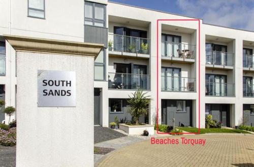 a building with a sign that reads south sands at BEACHES - South Sands beach house in Torquay