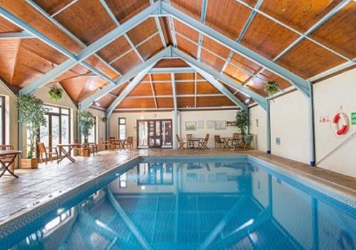 a swimming pool in a house with a wooden ceiling at Bovisand Lodge Holiday Park in Plymouth