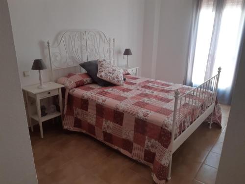 Schlafzimmer mit einem Bett mit einer roten und weißen Decke in der Unterkunft Alojamiento La Fuente in Fuenteheridos