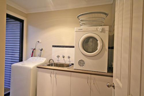 a kitchen with a washing machine and a sink at Treehouse-elevated nature setting, kids TV room in Quindalup