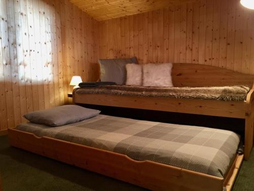 two beds in a room with wooden walls at Appartement Val d'Isère 6 personnes avec parking in Val dʼIsère