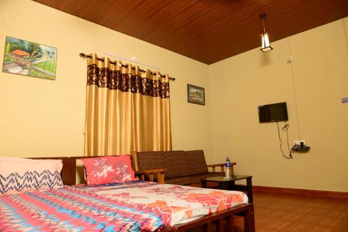 a bedroom with a bed and a couch and a television at jasmine land homestay in Udupi