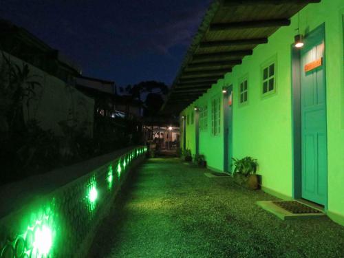 a row of buildings with green lights at night at Diógenes Pousada in Conceição da Ibitipoca