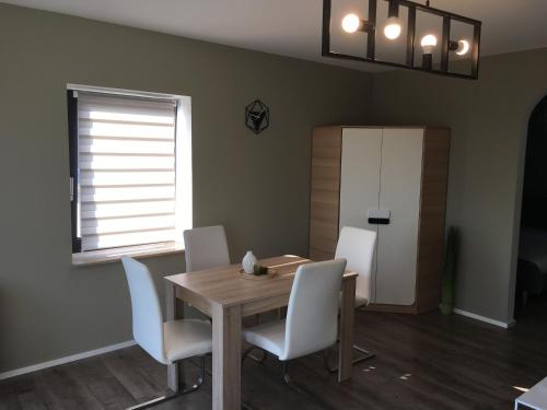 une salle à manger avec une table en bois et des chaises blanches dans l'établissement Three, à Coblence