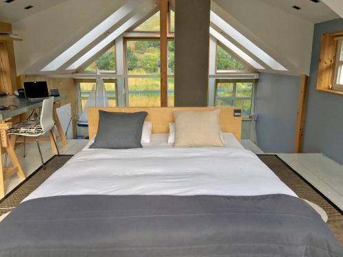 Cama grande en habitación con ventanas en Lofoten Fjord Lodge en Saupstad