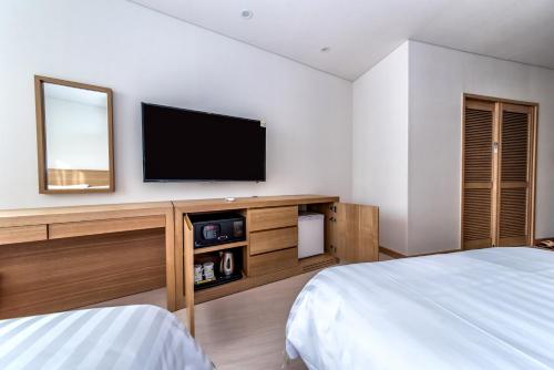 a bedroom with a flat screen tv on the wall at BK Hotel Jeju in Seogwipo