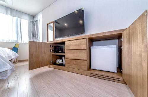 a bedroom with a flat screen tv on a wall at BK Hotel Jeju in Seogwipo