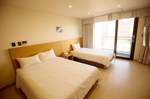 a hotel room with two beds and a window at BK Hotel Jeju in Seogwipo