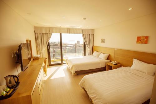 a hotel room with two beds and a window at BK Hotel Jeju in Seogwipo