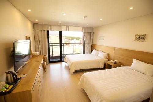 a hotel room with two beds and a television at BK Hotel Jeju in Seogwipo