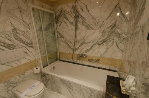 a bathroom with a tub and a toilet and a sink at Grand Hotel Tamerici & Principe in Montecatini Terme