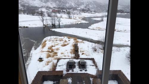 a view of a river in the snow from a window at Lofoten Fjord Lodge in Saupstad