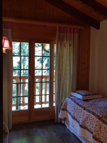 a bedroom with a bed and a sliding glass door at Rue de Bel-Aube Chalet Joli 10 in Crans-Montana
