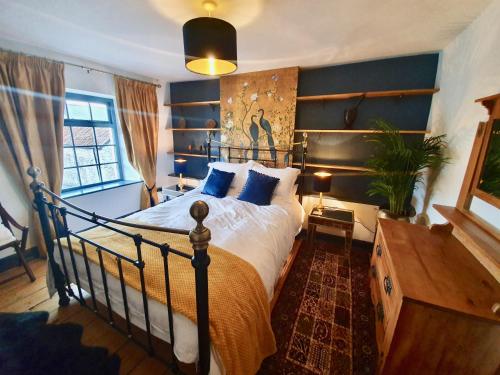 a bedroom with a large bed with blue walls at Fern Tree Cottage in Frome