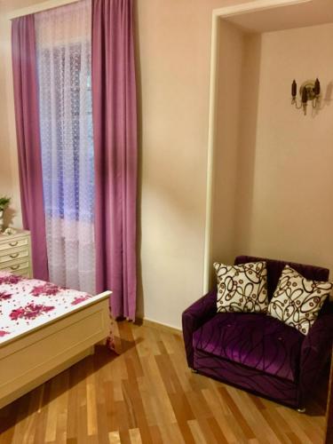 a bedroom with a purple couch and a window at Beauty in the Heart of the City in Tbilisi City