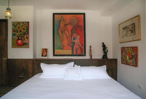 a bedroom with a white bed and a painting on the wall at Hotel Museo San Moritz in Bogotá