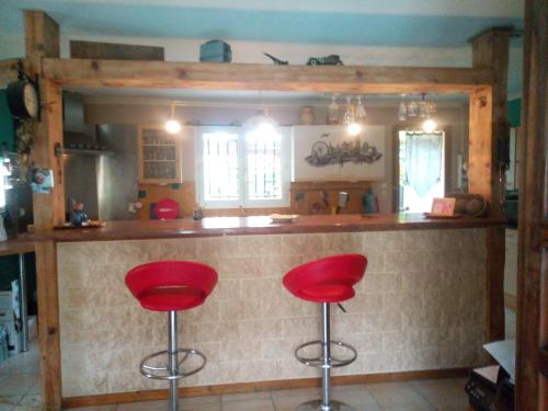 a kitchen with two red stools at a bar at Chez Mamiyo in Gallargues-Le-Montueux