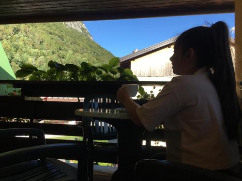 a woman sitting at a table with a cup of coffee at Residenza La Ciasa in Claut