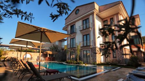 a hotel with a pool and chairs and an umbrella at Sukha Cunda Otel in Cunda