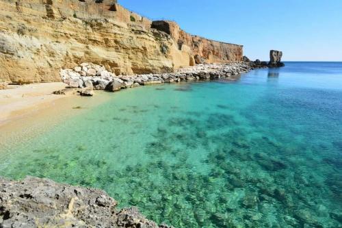 a beach with clear water next to a cliff at Monolocale Cora in Corsano