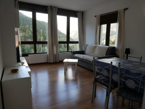 een woonkamer met een bank, een tafel en ramen bij El Tarter-Vacances Pirinenca in El Tarter