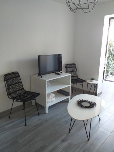 a living room with a tv and two chairs and a table at Joli studio res au calme en rez de jardin à Bandol. in Bandol
