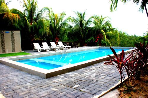 a swimming pool with two lounge chairs next to it at Pemandangan Indah Guest House - Look Out Point Villa- in Pantai Cenang