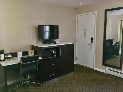 ミルフォードにあるScottish Inns Milfordのデスク、テレビ、ドレッサーが備わるホテルルームです。