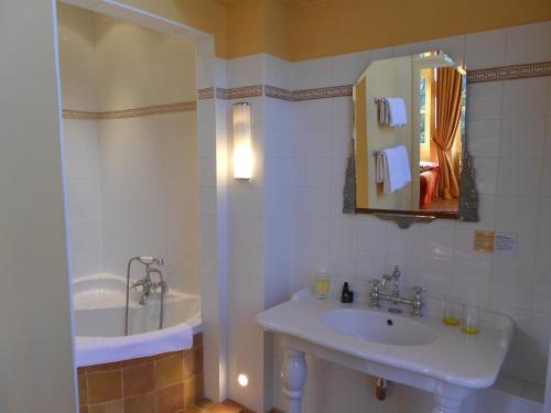 y baño con lavabo, espejo y bañera. en Chateau des Poccards, en Hurigny