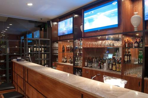 a bar with a television and a bar with bottles of alcohol at Las Ventanas Hotel Boutique in Ciudad del Este