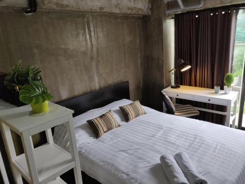 a bedroom with a white bed with a desk and a window at THE HOG in Bangkok Yai