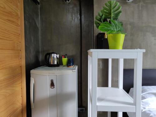 a white cabinet next to a white chair and a plant at THE HOG in Bangkok Yai