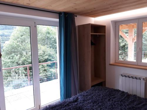 a bedroom with a bed and a large window at La maison des savoyards in Husseren-Wesserling