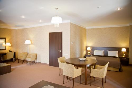 a hotel room with a bed and a table and chairs at Kainar Hotel in Shymkent