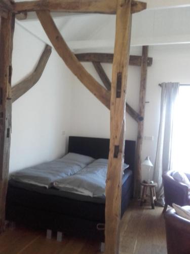 Bett in einem Zimmer mit Holzbalken in der Unterkunft Onder de Eiken in Noord-Sleen
