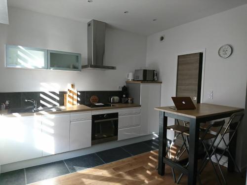 une cuisine avec des placards blancs et une table avec un ordinateur portable dans l'établissement La Ressourcerie du centre ville, à Lens