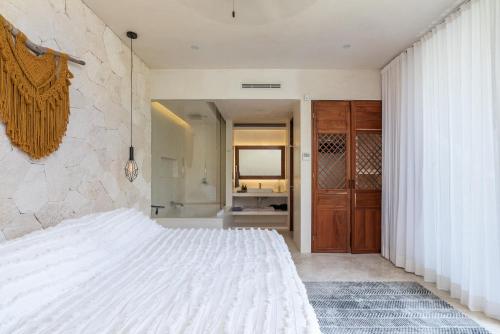 a bedroom with a white bed and a bathroom at Villa LaGú Masterpiece Tulum Jungle 5BR Pool & Spa in Tulum
