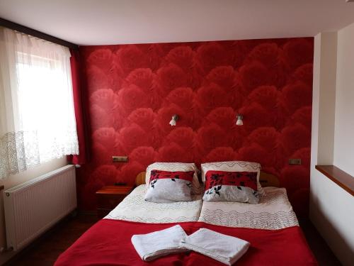 a bedroom with red walls and a bed with two pillows at Pokoje PETRA pod Bocianem in Supraśl