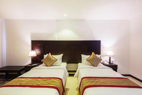 a hotel room with two beds and two lamps at Saveira Colombo in Colombo