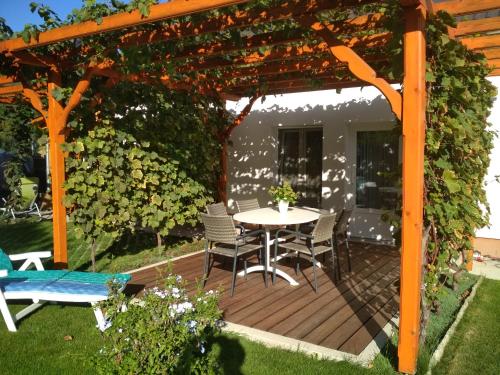 a wooden deck with a table and chairs under a pergola at Gólya Vendégház in Tiszaug