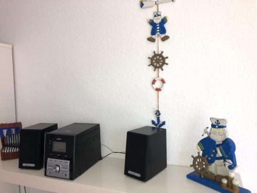 シェーンベルガー・シュトランドにあるFerienwohnung im Haus Sommerwindのデスク(スピーカー2台付)、電子レンジ、時計が備わります。