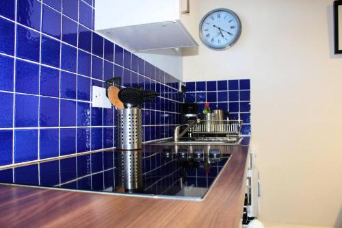 cocina de azulejos azules con fregadero y reloj en The Beachfront Retreat en Rush