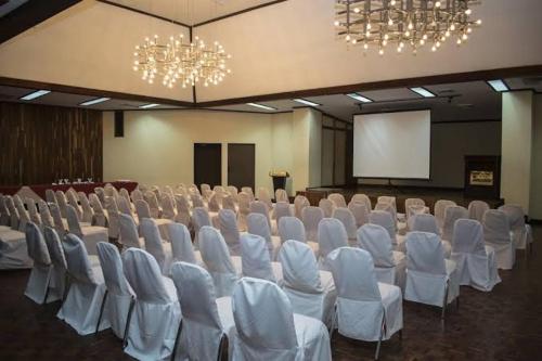 a large room with white chairs and a screen at Hotel Ambassador in San José