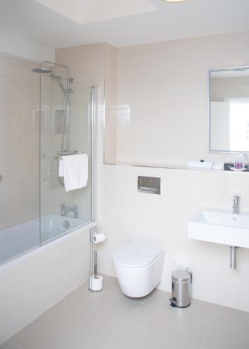 a white bathroom with a toilet and a sink at The Garrandarragh Inn in Mullinavat