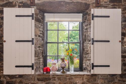 an open window with a vase of flowers on a table at The Garrandarragh Inn in Mullinavat