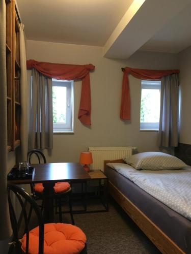a bedroom with a bed and a table and two windows at Pokoje Hotelowe Dux in Łódź